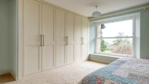 Cream bespoke wardrobes in a bedroom with bed to the right